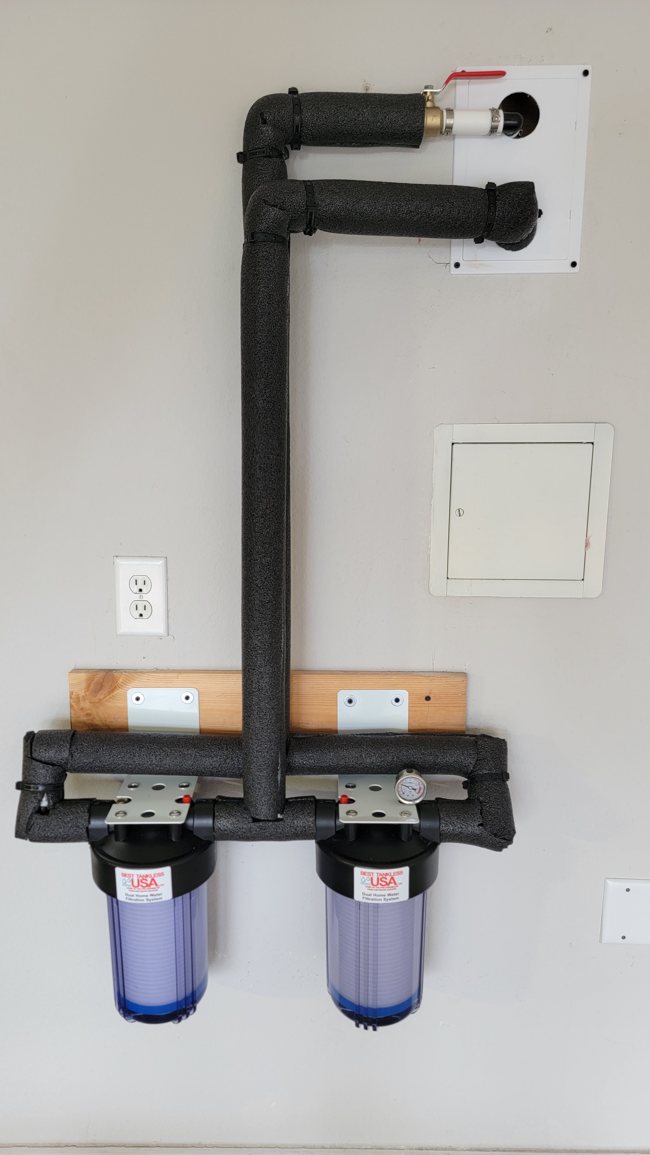 Dual 5-micron filter system installed by Best Tankless USA — two filter housings mounted on plywood board with insulated piping